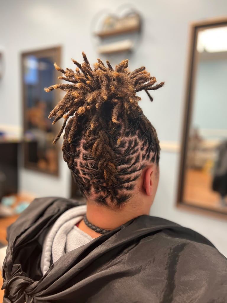 Interlocked locs swept up into a pineapple updo with honey-blonde tips